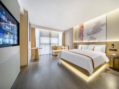 a bedroom with a large bed and a flat screen tv at GreenTree Eastern Hotel Nanjing Jiangning University in Jiangning