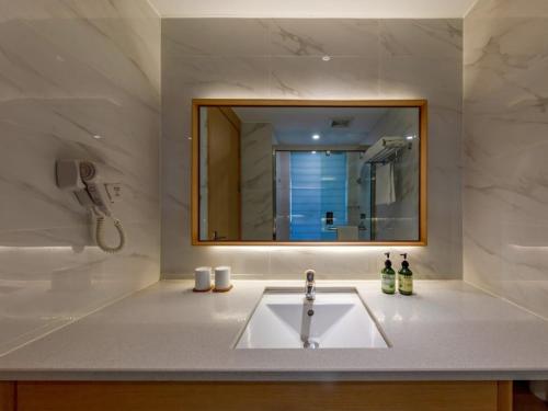 a bathroom with a sink and a mirror at GreenTree Eastern Hotel Jiaxing Jiangnan Moore Store in Jiaxing