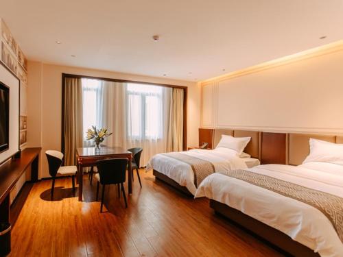 a hotel room with two beds and a desk at GEM Hotel Bozhou College in Bozhou