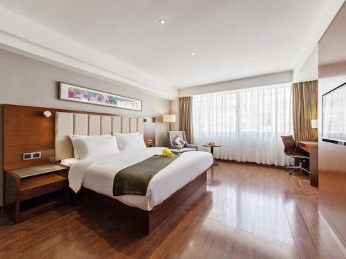 a hotel room with a large bed and a desk at GreenTree Eastern Hotel Yiwu International Trade City in Yiwu