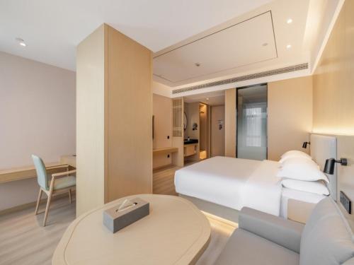 1 dormitorio con cama blanca, escritorio y mesa en Deep Sleep Hotel Hangzhou Dajiang East Haide Xingang Center en Hangzhou