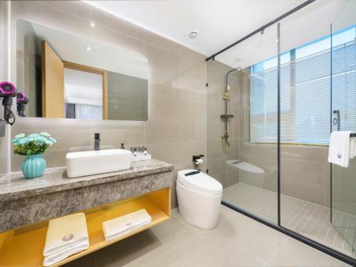 een badkamer met een wastafel, een toilet en een douche bij Geli Hotel Nanning East Railway Station in Nanning