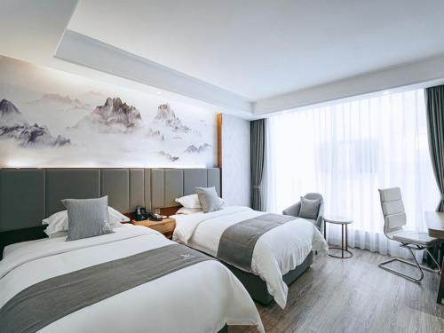 ZhenningにあるGreenTree Eastern Hotel Anshun Anshun Zhenning Huangguoshuのベッド2台とデスクが備わるホテルルームです。