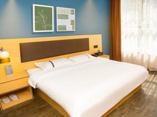 1 cama blanca grande en un dormitorio con paredes azules en Geli Hotel Hefei Modian University Mengxi Town, en Hefei