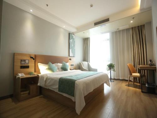 a bedroom with a bed and a desk and a window at GreenTree Inn Anqing East Yingbin Road High-Speed Railway Station in Anqing