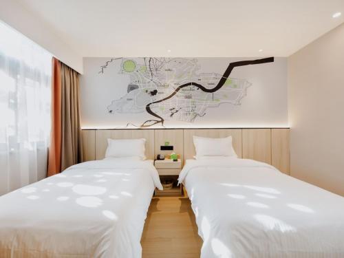 2 camas en una habitación con un mapa en la pared en Vatica Hotel Shuyang Central Mall Nanjing Road, en Shuyang