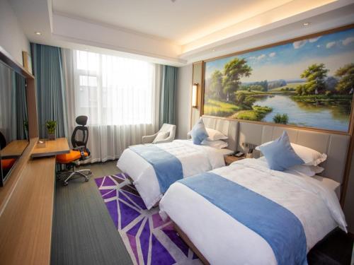 BinzhouにあるGreenTree Eastern Hotel Binzhou Zhonghai International Convention and Exhibition Centerのベッド2台が備わる客室で、壁には絵画が飾られています。