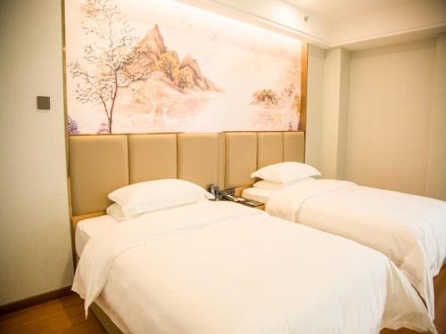 two beds in a room with a painting on the wall at GreenTree Eastern Hotel Hebi Jun County Passenger Station in Xun