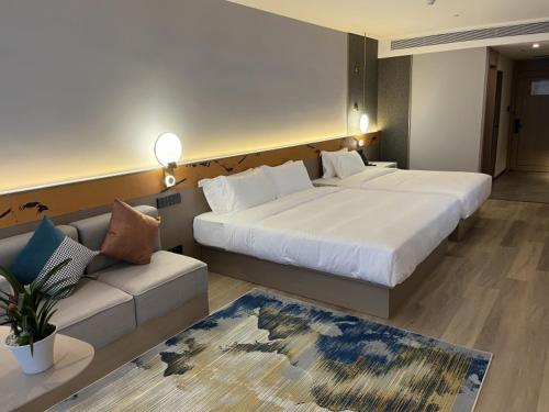 a hotel room with two beds and a couch at GreenTree Eastern Hotel Yiwu International Trade City in Yiwu