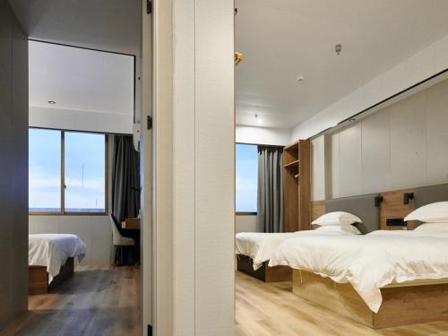 a hotel room with two beds and a mirror at GreenTree Inn Express Hotel Suzhou Taicang West Nanjing Road in Taicang