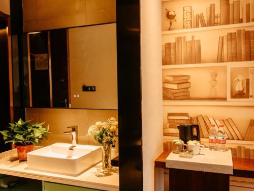 a bathroom with a sink and a mirror and books at GEM Hotel Bozhou College in Bozhou