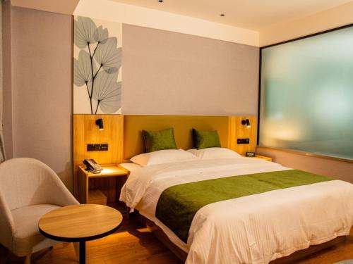 a bedroom with a large bed with a chair and a table at GreenTree Inn Express Hotel Fuyang Development Zone Oriental Pearl in Fuyang