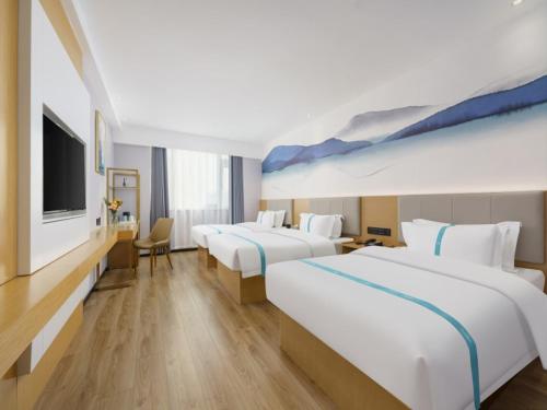 a hotel room with two beds and a flat screen tv at VX Hotel Dalian Zhoushuizi Airport in Dalian