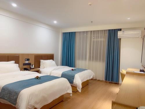2 bedden in een hotelkamer met blauwe gordijnen bij GreenTree Inn Guangdong Zhanjiang Donghai Island in Zhanjiang
