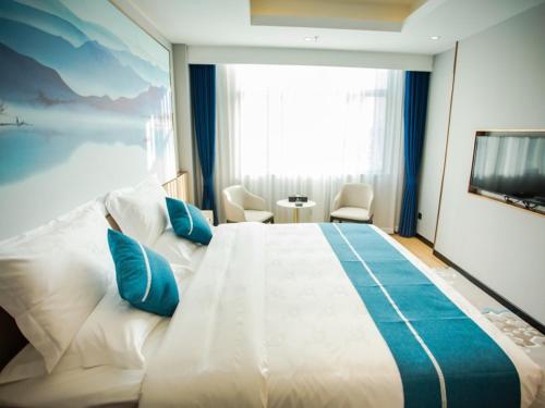 a bedroom with a large white bed with blue pillows at GreenTree Eastern Hotel Tongling Yi'an Government in Xihu