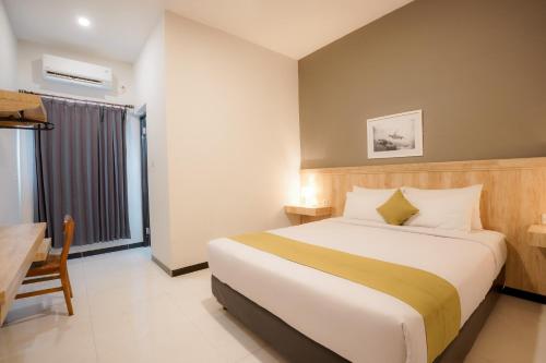 ラブハン・バジョにあるEl Ora Hotel & Eatery Labuan Bajoのベッド、デスク、窓が備わるホテルルームです。