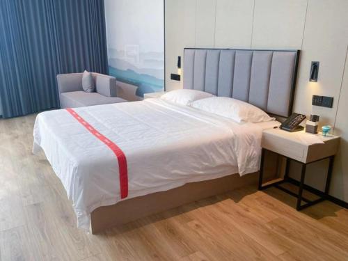Un dormitorio con una cama grande y un teléfono en una mesa. en GreenTree Eastern Hotel Fuyang Jieshou Railway Station East Xinyang Road, en Xiaosongzhuang