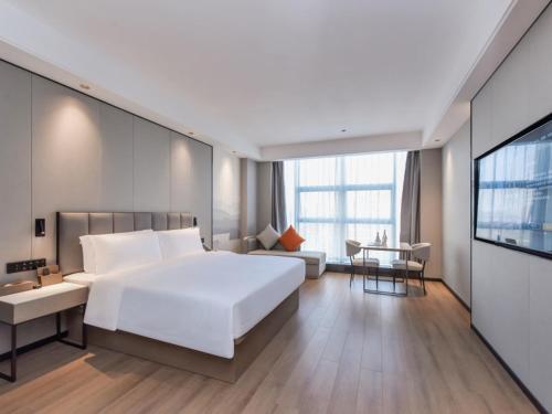 ein Schlafzimmer mit einem großen weißen Bett und ein Wohnzimmer in der Unterkunft GreenTree Eastern Hotel Chongqing Jiefangbei International Airport Lushan Subway Station in Chongqing