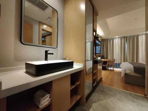 a bathroom with a sink and a mirror and a bed at GreenTree Eastern Hotel Xinjiang Urumqi Renmin Road in Ürümqi
