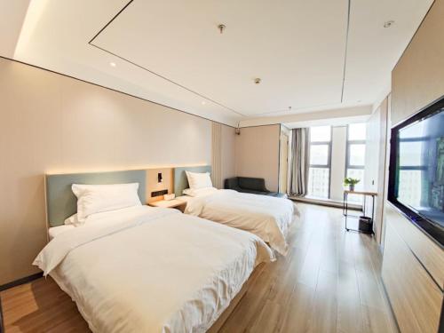 Duas camas num quarto com uma janela grande em GreenTree Inn Lanzhou Zhongchuan Airport em Hejialiang
