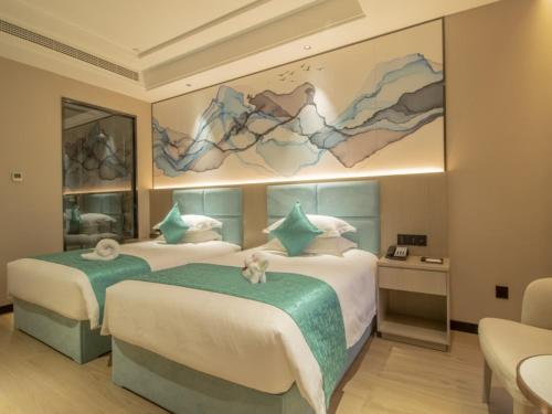 a hotel room with two beds and a painting on the wall at GreenTree Eastern Hotel Hainan Free Trade Port Jiangdong New District Meilan Airport in Haikou