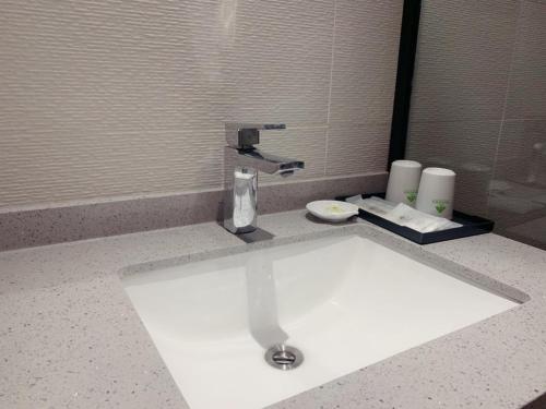 a bathroom sink with a faucet on a counter at GreenTree Inn Guangdong Zhanjiang Donghai Island in Zhanjiang