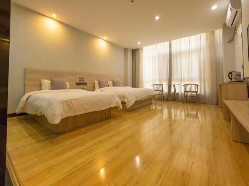 a bedroom with two beds and a wooden floor at Geli Hotel Xuzhou Government Olympic Sports Center in Xuzhou