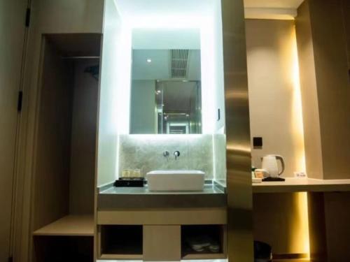 W łazience znajduje się umywalka i lustro. w obiekcie VX Hotel Yichun Yuanzhou Government High-Speed Railway w mieście Yichun