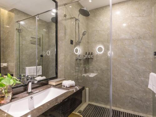 a bathroom with a tub and a shower and a sink at GreenTree Eastern Hotel Shenzhen Pinghu Hua'nan City Hehua Subway Station in Longgang