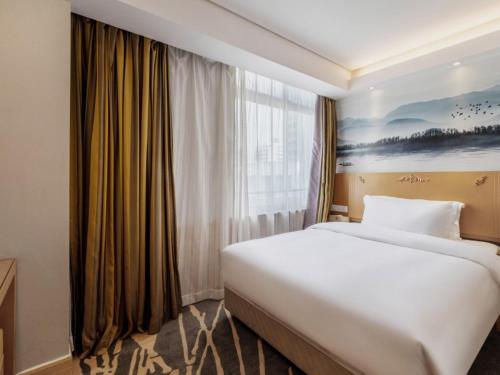 um quarto de hotel com uma cama grande e uma janela em GreenTree Eastern Hotel Shenzhen Futian Civic Center Jingtan Subway Station em Shenzhen