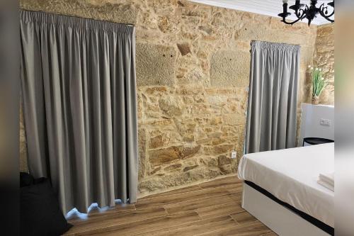 een slaapkamer met een bed en een stenen muur bij Casa Rural Depende in Vilagarcia de Arousa