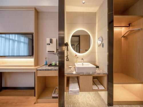 two pictures of a bathroom with a sink and a mirror at VX Hotel Fuyang Railway Station East Beijing Road in Fuyang