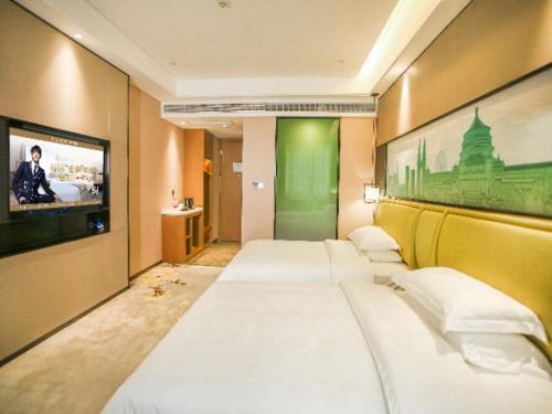 a row of beds in a room with a tv at GreenTree Eastern Hotel Chongqing Jiefangbei Children's Hospital in Chongqing