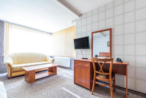 a room with a desk with a mirror and a bed at Семеен хотел Кристал in Smolyan