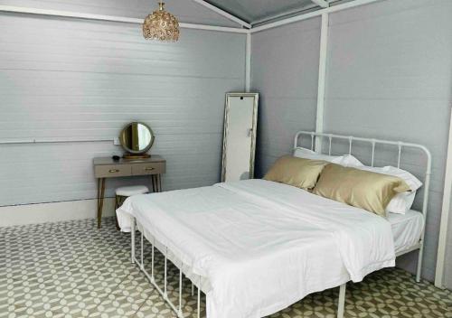 - une chambre avec un lit et une table avec un miroir dans l'établissement British Granny's Cottage in Penang Island, à Jelutong