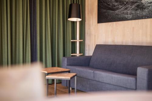 a living room with a blue couch and a lamp at Hotel Arlmont 4 Stern Superior in Sankt Anton am Arlberg