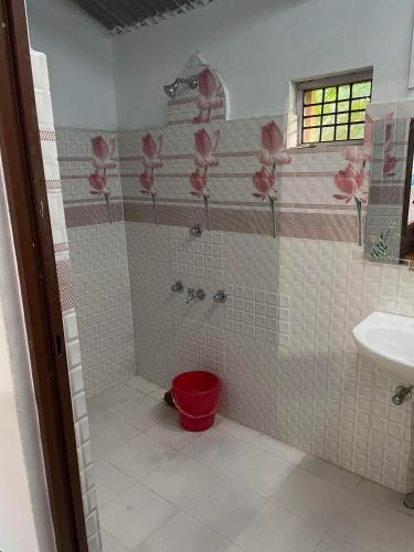 a bathroom with a shower with pink flowers on the wall at Good Karma Homestay in Bhurkīā