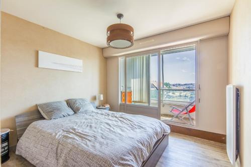 une chambre avec un lit et une grande fenêtre dans l'établissement La Vue Marine - Appartement vue mer, à Courseulles-sur-Mer