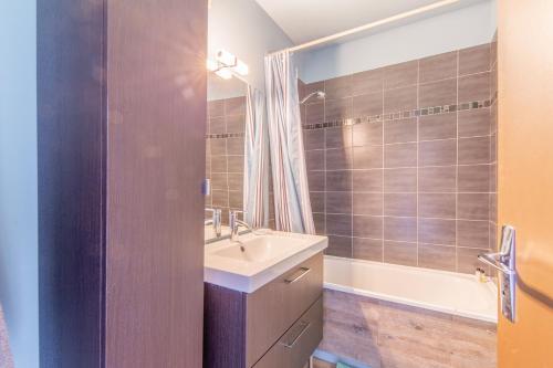 une salle de bain avec un lavabo et une baignoire dans l'établissement La Vue Marine - Appartement vue mer, à Courseulles-sur-Mer