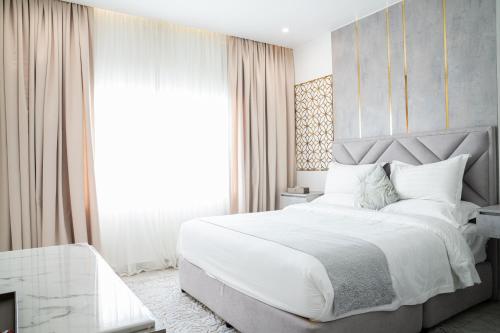 a bedroom with a large white bed and a window at Le Levels Residency in Dammam