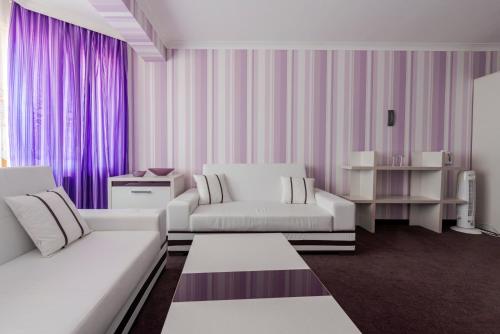 a living room with two white couches and purple curtains at Семеен хотел Кристал in Smolyan