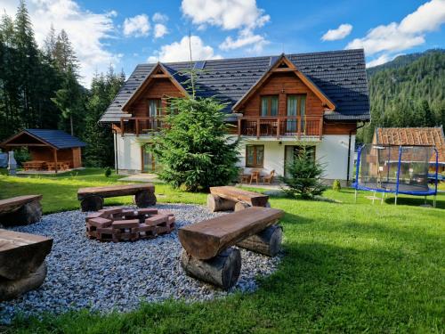 a log cabin with a firepit and benches in the yard at Darmilus apartmány in Belá
