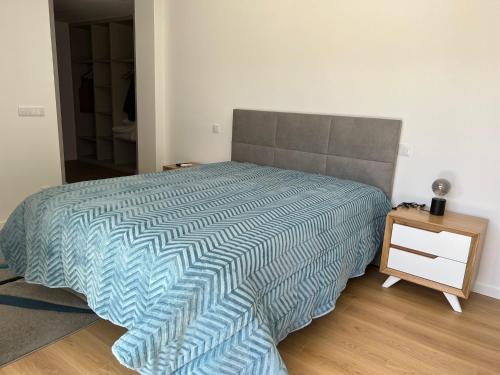 um quarto com uma cama com um edredão azul e uma mesa em A Casa do Fiúza em Moreira do Lima