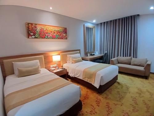um quarto de hotel com duas camas e um sofá em Grand Serela Yogyakarta by KAGUM Hotels em Yogyakarta