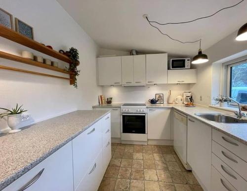 eine weiße Küche mit einer Spüle und einem Herd in der Unterkunft Pia´s Guesthouse in Askeby