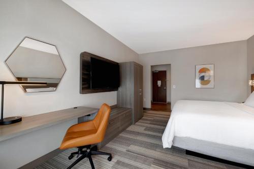 a hotel room with a bed and a desk with a television at Holiday Inn Express & Suites - Glendale Downtown in Glendale