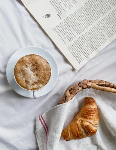 a cup of coffee and a pastry on a bed at Ciauru Design B&B in Messina