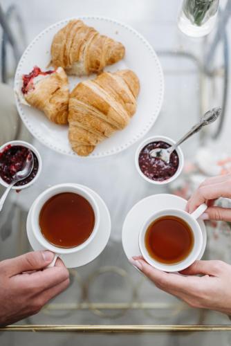 two people holding cups of tea and a plate of pastries at Ciauru Design B&B in Messina