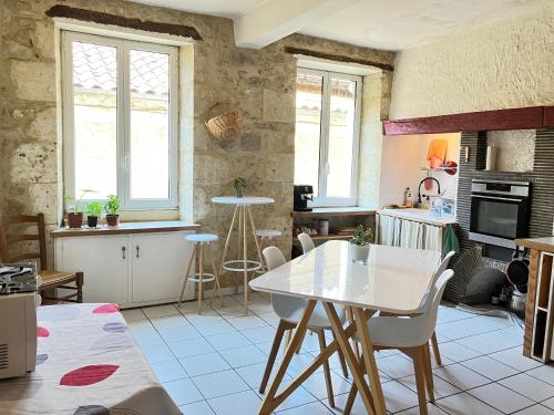 a kitchen with a white table and chairs at Au dessus des arcades in Vic-Fezensac