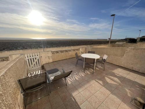 une terrasse avec une table et des chaises et la plage dans l'établissement Appartement face à la mer, à Saint Pierre La Mer